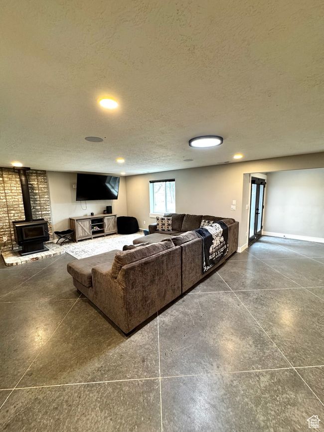 Living room featuring a wood stove, a textured ceiling, recessed lighting, and baseboards | Image 22