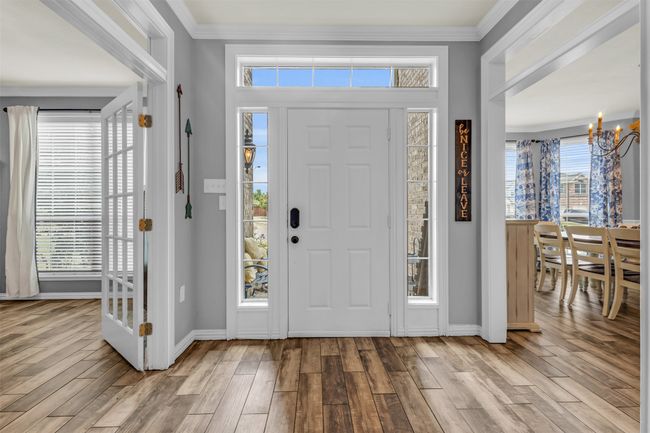 Entrance foyer featuring light wood-type flooring, ornamental molding, and a notable chandelier | Image 21