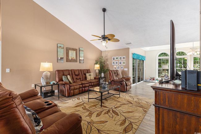 Living area with a ceiling fan, vaulted ceiling, and light wood-style floors | Image 12