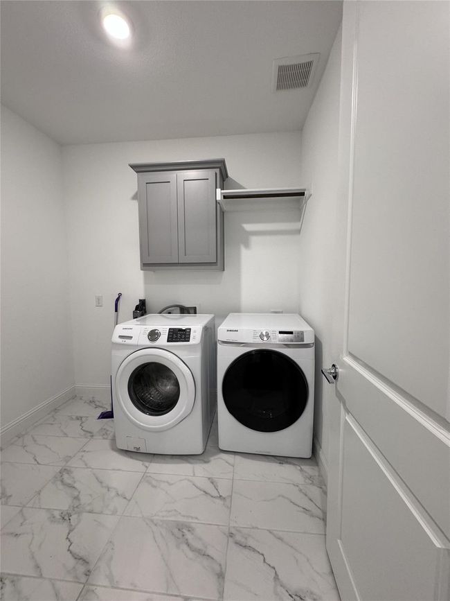 Laundry room featuring washing machine and dryer, cabinet space, and light marble finish floors | Image 10