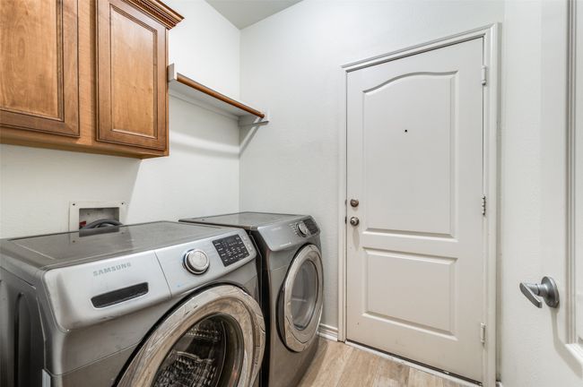 Laundry area featuring separate washer and dryer, light wood-style flooring, and cabinet space | Image 22