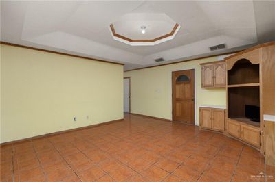 Unfurnished living room with built in desk, light tile patterned flooring, and a raised ceiling | Image 3