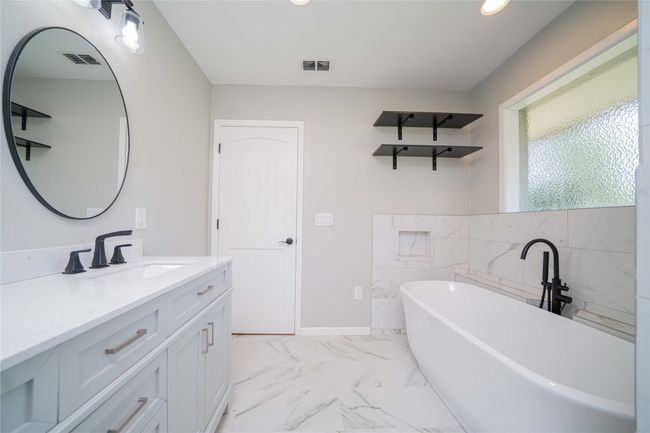 Bathroom featuring vanity, a freestanding tub, marble finish flooring, recessed lighting, and tile walls | Image 26