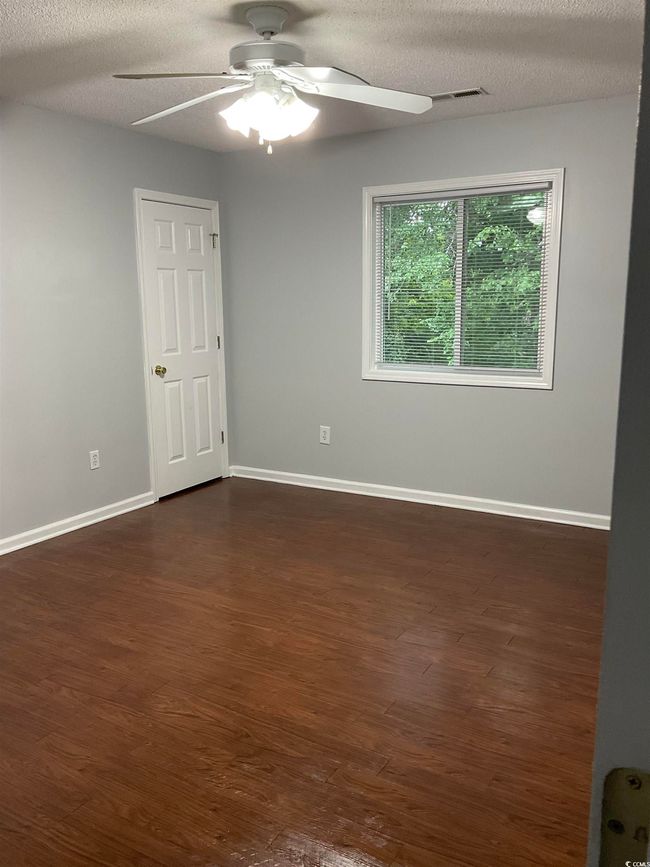 Empty room featuring a ceiling fan, dark wood-type flooring, and a textured ceiling | Image 6
