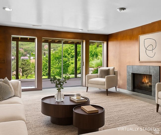 Carpeted living area featuring healthy amount of natural light, a fireplace, and wooden walls | Image 30