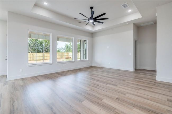 Empty room featuring a tray ceiling, light wood finished floors, ceiling fan, and recessed lighting | Image 5