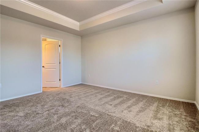 Carpeted empty room with ornamental molding, baseboards, and a tray ceiling | Image 24