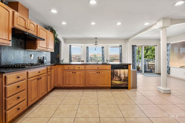 Kitchen featuring dishwasher, decorative columns, recessed lighting, black honed granite countertops, and gas stovetop | Image 13