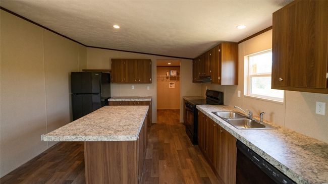 Kitchen featuring black appliances, vaulted ceiling, light countertops, dark wood-style flooring, and under cabinet range hood | Image 28