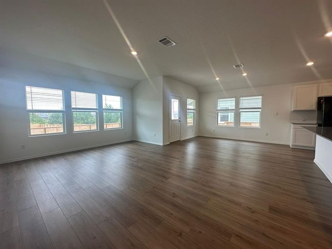 Unfurnished living room featuring baseboards, dark wood-type flooring, lofted ceiling, and recessed lighting | Image 18