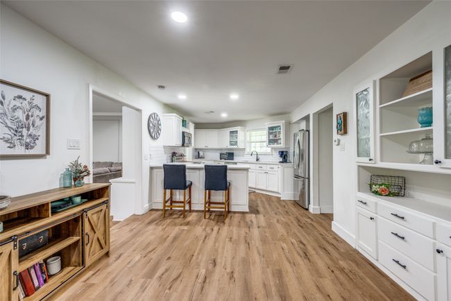 Kitchen featuring stainless steel appliances, light wood finished floors, a kitchen bar, white cabinets, and recessed lighting | Image 6