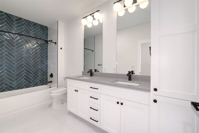 Full bath featuring double vanity, bathtub / shower combination, toilet, and tile patterned flooring | Image 10
