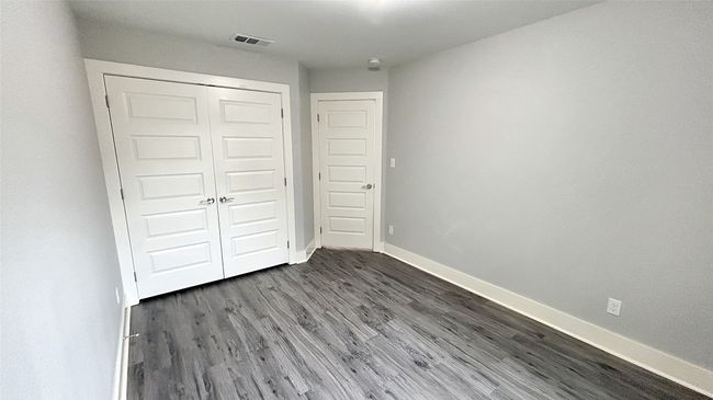 Unfurnished bedroom with dark wood-style flooring and a closet | Image 9