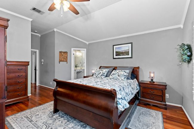 Bedroom with connected bathroom, crown molding, wood-type flooring, vaulted ceiling, and ceiling fan | Image 23