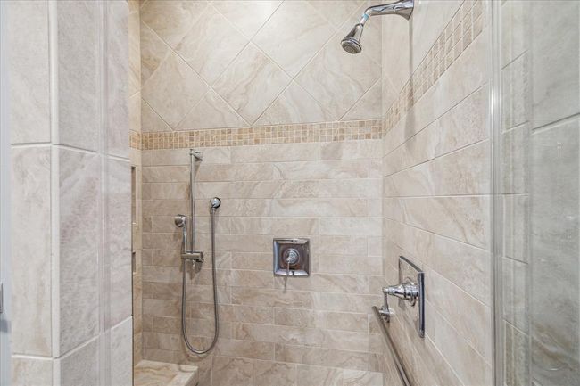 RELAX FROM A LONG DAY IN THIS SEAMLESS SHOWER OFFERING SEATING AND DUAL SHOWER HEADS, AND CUSTOM TILE | Image 30