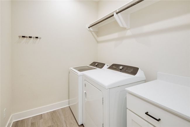 Laundry room featuring independent washer and dryer, light wood finished floors, and baseboards | Image 19