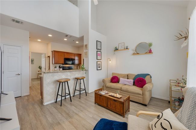Living area featuring light wood finished floors, a towering ceiling, and recessed lighting | Image 4