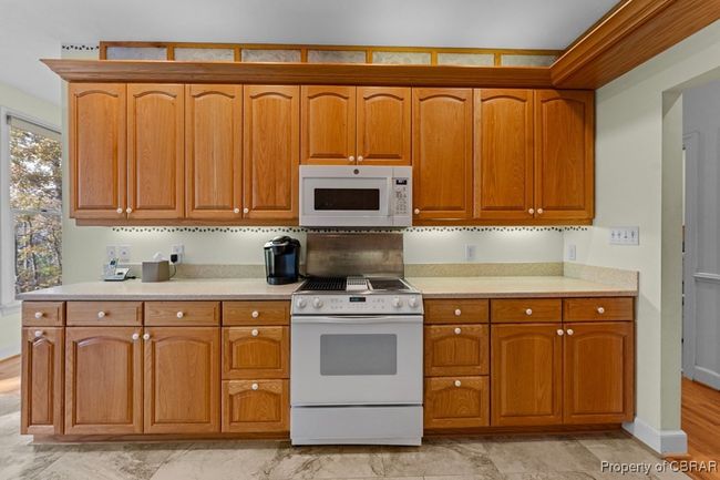 Kitchen featuring white appliances, light countertops, and brown cabinetry | Image 22