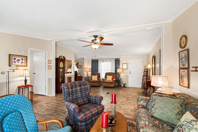 Living area with wood finished floors, ceiling fan, and a textured ceiling | Image 16