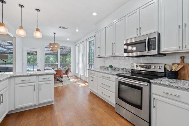 Kitchen with appliances with stainless steel finishes, light wood finished floors, white cabinetry, and recessed lighting | Image 7