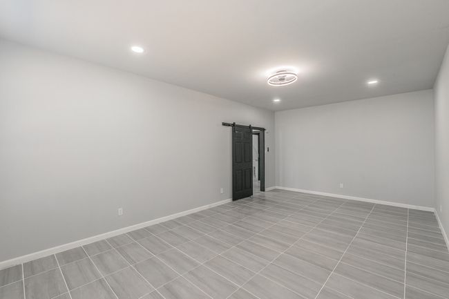 Spare room featuring baseboards, a barn door, and recessed lighting | Image 9