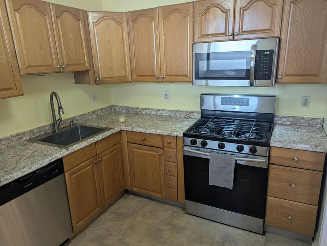 Kitchen featuring appliances with stainless steel finishes, light stone counters, and brown cabinets | Image 6