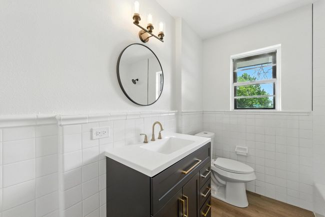 Bathroom featuring tile walls, vanity, wood finished floors, a tub, and a wainscoted wall | Image 21