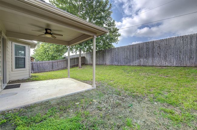 Fenced backyard with a ceiling fan and a patio | Image 27