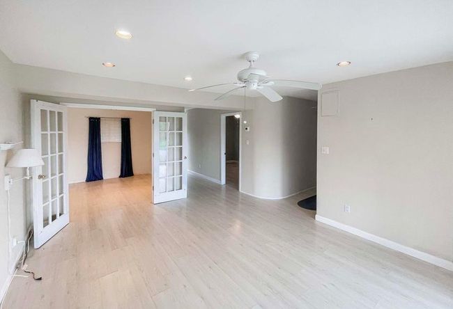 Empty room featuring light wood finished floors, baseboards, recessed lighting, a ceiling fan, and french doors | Image 17