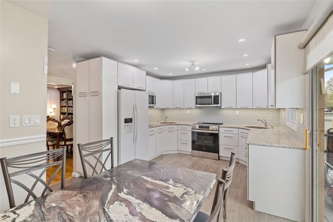 Kitchen with a sink, decorative backsplash, stainless steel appliances, light wood-style flooring, and light stone countertops | Image 17