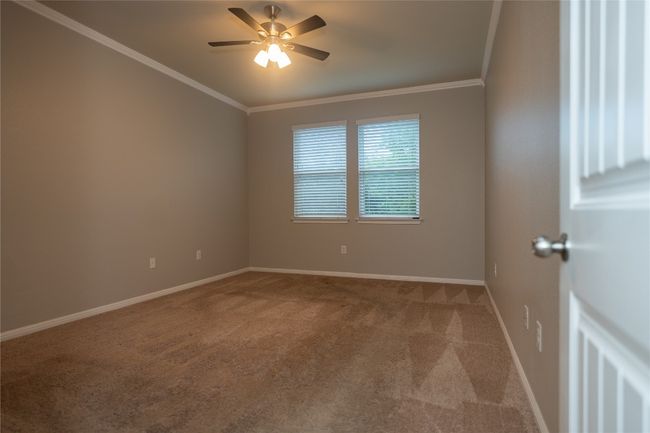 Carpeted empty room with crown molding, ceiling fan, and baseboards | Image 12