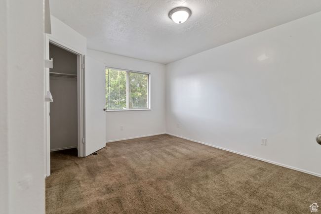 Unfurnished bedroom featuring carpet, a textured ceiling, and a closet | Image 18