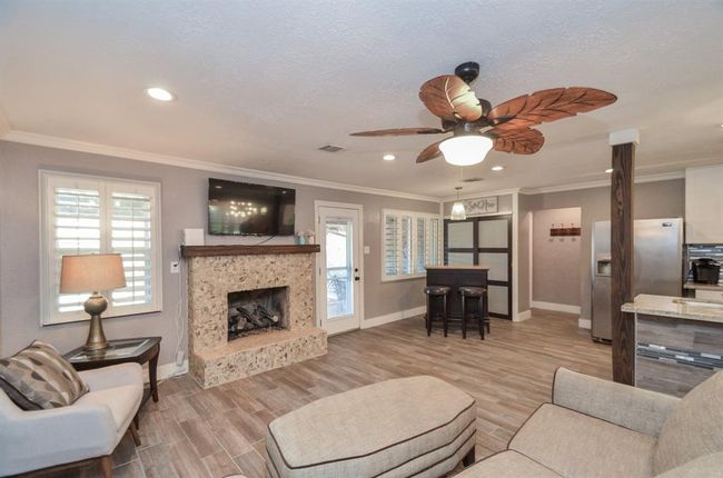 Another view of the living room- plantation shutters, dining area (currently used as a bar area) and frosted sliding doors opens to a hidden pantry/storage area | Image 11