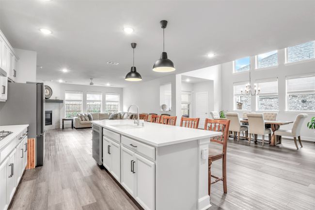 Kitchen featuring a breakfast bar, an island with sink, sink, white cabinets, and hanging light fixtures | Image 12