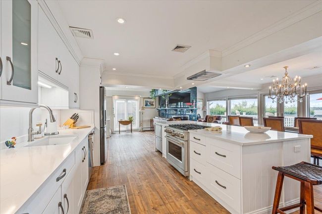 Kitchen with appliances with stainless steel finishes, a chandelier, light countertops, healthy amount of natural light, and ornamental molding | Image 9