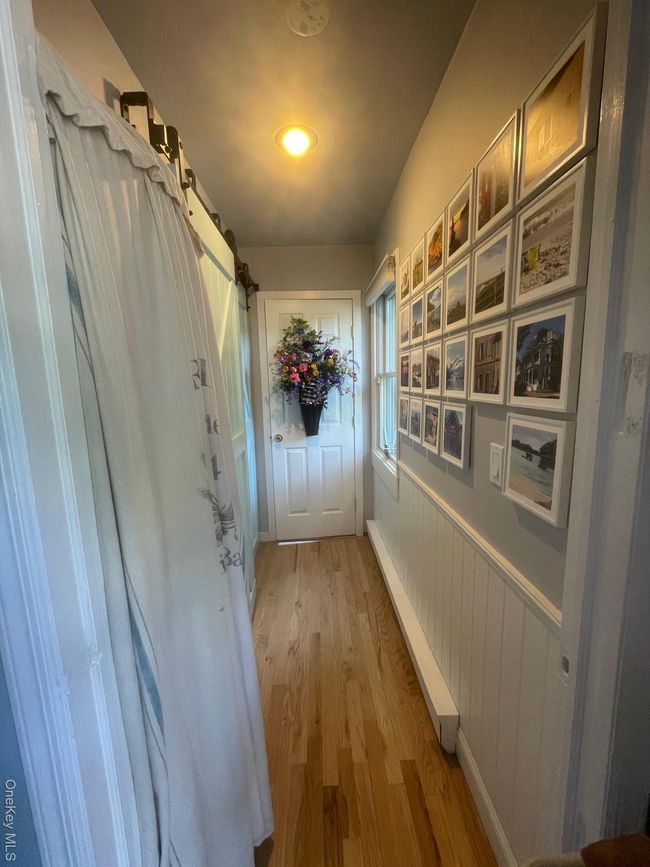 Entryway with wood finished floors, a baseboard radiator, a wainscoted wall, and a barn door | Image 13