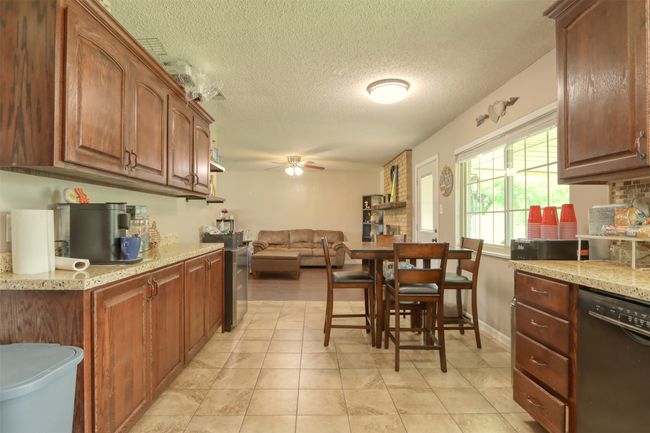 Kitchen featuring dishwasher, ceiling fan, a textured ceiling, light stone countertops, and open floor plan | Image 19