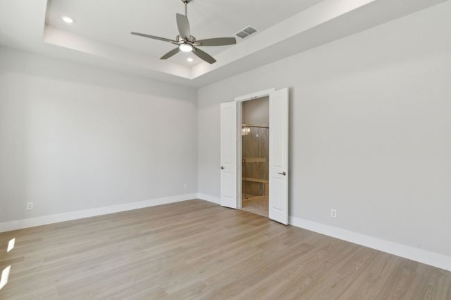Empty room featuring a tray ceiling, light wood-style floors, recessed lighting, and ceiling fan | Image 18