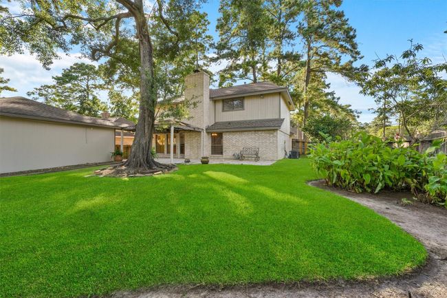 This photo showcases a charming two-story home with a brick facade, surrounded by a lush, well-maintained lawn and mature trees. The backyard is spacious, offering ample room for outdoor activities and relaxation. | Image 24