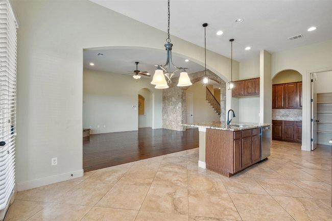 Kitchen with arched walkways, light tile patterned floors, a ceiling fan, recessed lighting, and light stone countertops | Image 25
