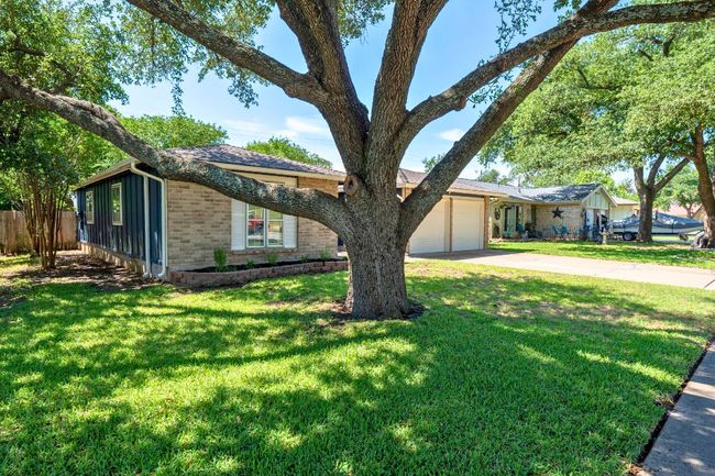 Ranch-style house with brick siding, concrete driveway, a garage, and board and batten siding | Image 5