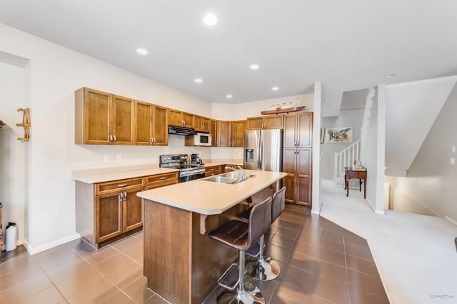 Kitchen featuring dark tile patterned floors, stainless steel appliances, light countertops, and a sink | Image 7