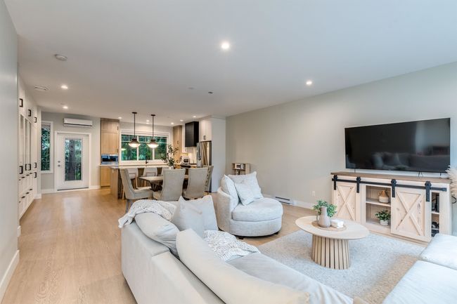 Living room with recessed lighting, a baseboard radiator, an AC wall unit, baseboards, and light wood-type flooring | Image 8