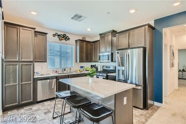 Kitchen with a sink, stainless steel appliances, visible vents, a kitchen island, and dark brown cabinets | Image 17