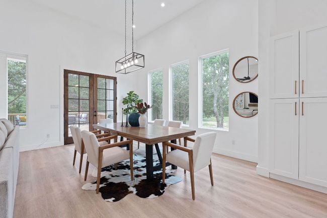 Dining space with baseboards, french doors, light wood type floors, and a towering ceiling | Image 10