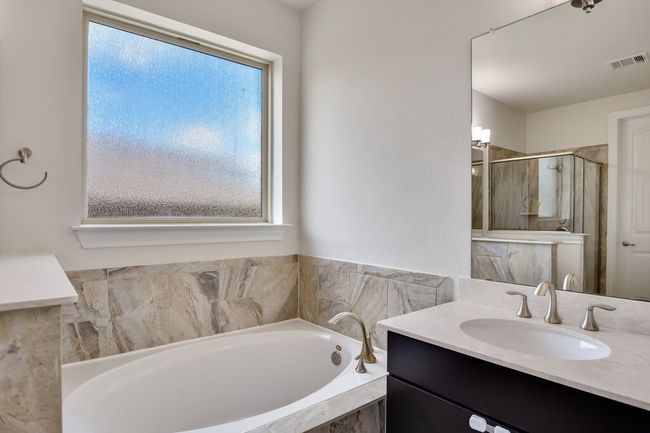 Bathroom featuring vanity, a bath, and a stall shower | Image 26