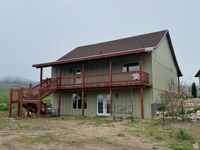 Rear view of house with french doors, a deck, board and batten siding, and stairs | Image 27