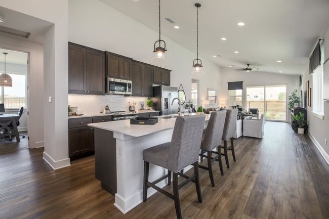 Kitchen featuring visible vents, dark brown cabinetry, a breakfast bar, dark wood-style floors, and stainless steel appliances | Image 4