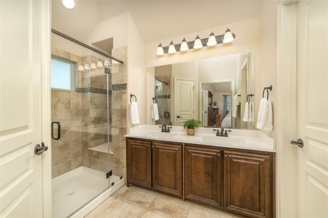 Ensuite bathroom featuring a shower stall, double vanity, and vaulted ceiling | Image 26