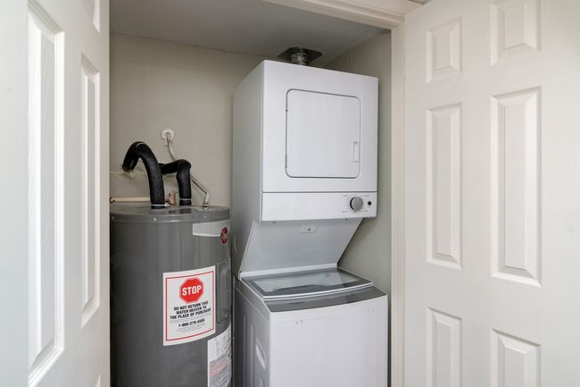 Washroom with water heater, stacked washer / drying machine, and laundry area | Image 13